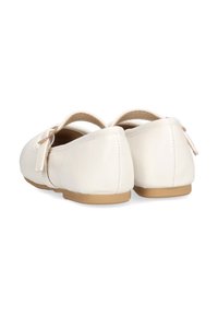 Zapatos de cuero blancos con forma redondeada, que cuentan con una correa en la parte posterior y un pequeño lazo decorativo. La suela es de color marrón claro, con costuras visibles.