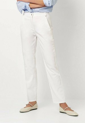White cotton trousers with a straight cut, two side pockets, and subtle stitching details. Paired with beige flats featuring a strap.