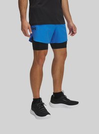 Blue athletic shorts layered over black compression shorts, paired with black and white running shoes. Black t-shirt completes the outfit.