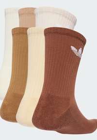 Neljä ribbittyä crew-sukkaa beige, vaaleanruskea, kerma ja tummanruskea, joissa on valkoinen logo yksityiskohtana resorissa.