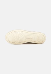 Suola di sneaker bianca con texture ondulata e motivo circolare. Presenta un logo in rilievo "AUTRY" vicino al tallone. Nessun segno di usura visibile.