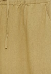 Beige linnedragt med elastisk talje og snoretræk. Har sidelommer og en struktureret stofoverflade for en blød finish.