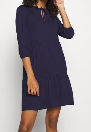 Marineblaues Kleid aus weichem Stoff mit rundem Ausschnitt, Bindeband-Detail, Dreiviertelärmeln und einem Stufendesign am Rock.