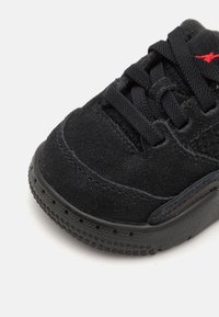 Svart semsket sneakers med teksturert overflate, rund tå og svarte snøringer. Har en gummisåle med stjernemønsterdetaljer.