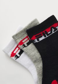 Tre paia di calzini da lavoro: uno bianco, uno grigio e uno nero. Ciascuno presenta un bordo con logo colorato con accenti rossi e grigi. Tessuto testurizzato.