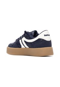 Zapatilla de color azul marino con acentos en blanco, fabricada en material sintético suave. Presenta una suela gruesa color beige y un diseño con cordones.