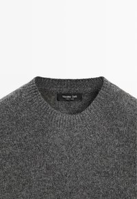Maglione grigio a maglia con scollo rotondo, caratterizzato da un tessuto strutturato. Etichetta visibile sul collo, con la scritta "Massimo Dutti, Made in Turkey".