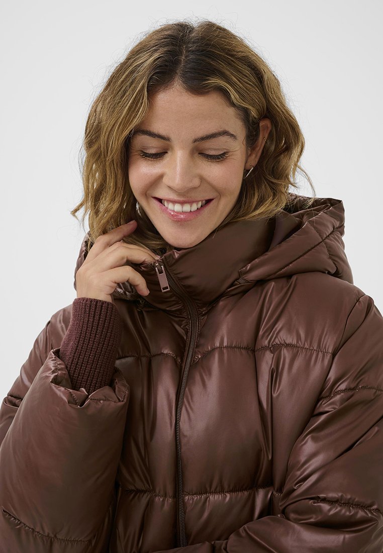 Braune Daunenjacke mit Kapuze, gestepptem Design und Reißverschluss. Sie verfügt über gerippte Strickbündchen und eine glatte, glänzende Oberfläche.