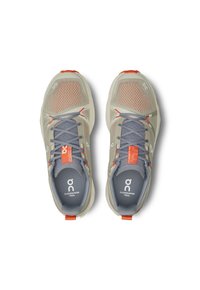 Lichtgrijze trailrunning schoenen met een bovenwerk van mesh, oranje accenten en grijze veters. Kenmerken zijn een gevoerde zool en een logo op de binnenzool.