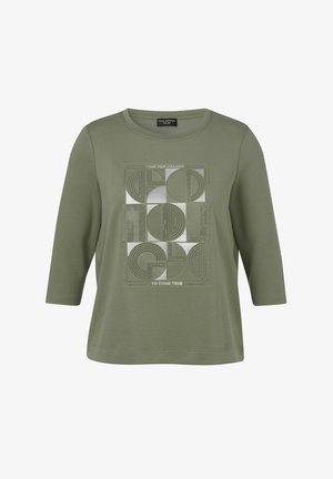 Olijfgroen shirt met driekwart mouwen, versierd met geometrische vormen en de tekst "Tijd om dromen waar te laten worden" op de voorkant.
