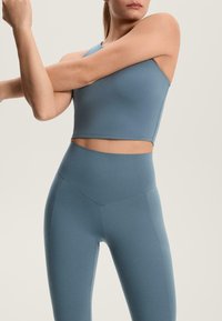 Modra športna kratka majica z enim pasom in visokim pasom legicami z geometričnim šivom.