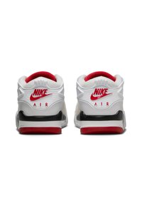 Zapatillas Nike blancas con acentos rojos, con cuellos de talón texturizados, una media suela negra y un marcado logotipo en la parte trasera.