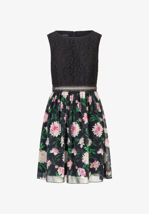 Zwarte kant jurk met een aansluitende lijfje, rok met bloemmotief in donkere kleuren, geaccentueerd door een metallic riem op de taille.