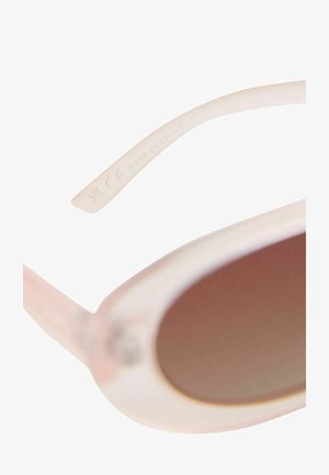 Akiniai nuo saulės su skaidriu šviesiai rožiniu rėmeliu, tamsiai tonuotais objektyvais ir išgraviruotais detalėmis ant šventinio šono. Tekstas skelbia "Pagaminta Kinijoje."