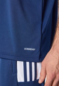 Camiseta atlética de color azul marino, hecha de tela que absorbe la humedad, con un logo blanco de "AEROREADY" y un diseño elegante con textura sutil.
