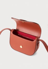 Borsa a tracolla in pelle marrone chiaro con forma curvata, chiusura a scatto dorata e interno rosso. Include un compartimento con cerniera per l'organizzazione.
