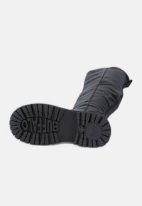 Bota negra hasta la mitad de la pantorrilla con suela gruesa y con dibujo, que presenta la marca "BUFFALO" en la parte inferior, mostrada sobre un fondo blanco liso.