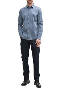 Blauwe gemusterde overhemd met kraag, lange mouwen en een ontspannen pasvorm, gecombineerd met donkere denimbroek en zwarte schoenen.