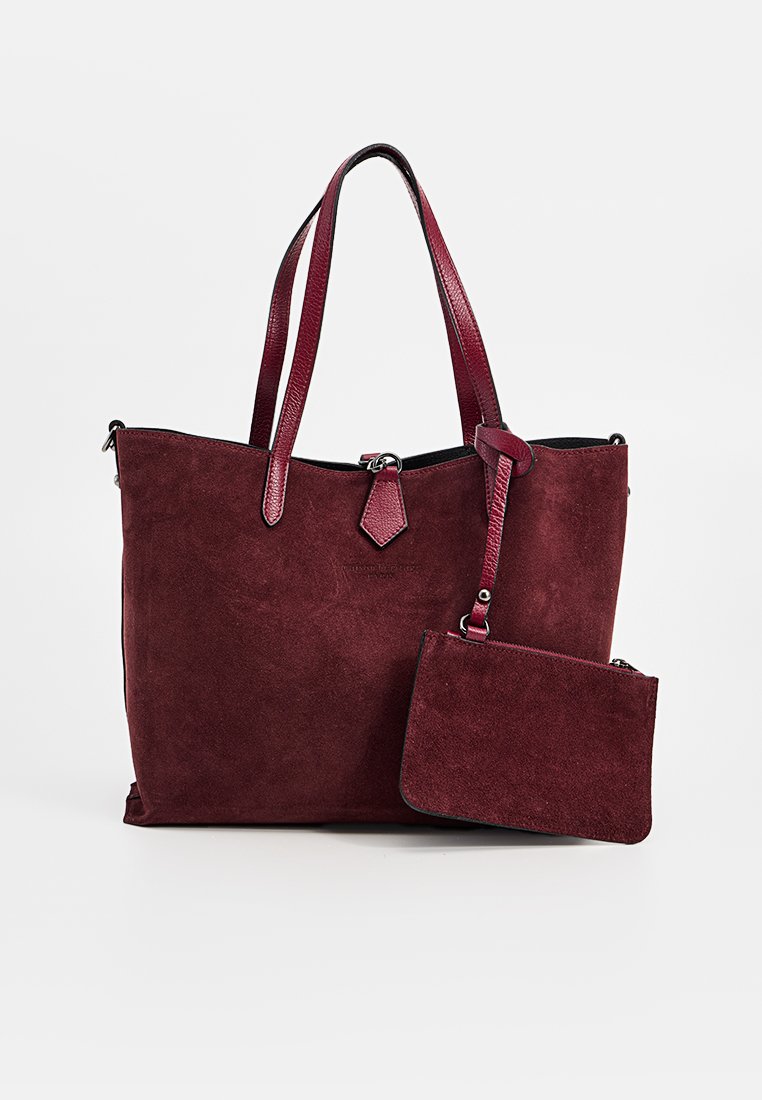 Bordeauxfarbene Wildleder-Tote mit passendem abnehmbarem Beutel, doppelten Ledergriffen und silberfarbener Hardware auf einem weißen Hintergrund.