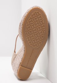 Espadrille slip-on beige avec dessus tissé, semelle extérieure texturée et design plat. Marque embossée sur le côté de la semelle.