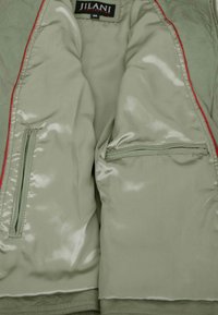 Light green jacket interior with two zippered pockets and a black "Jilani Collection" label with size 38 at the collar.