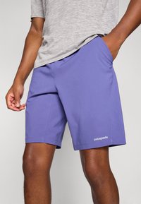 Patagonia men’s shorts in solid lavender, made of lightweight fabric, featuring side pockets and subtle branding near the hem.