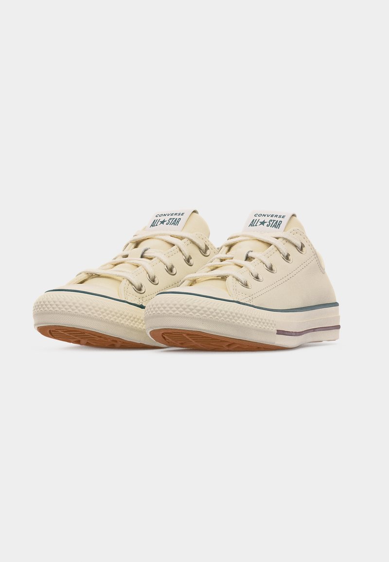 Paar beige niedrige Converse All Star Sneaker mit weißen Gummisohlen und brauner Profilsohle, geschnürt und nebeneinander positioniert.