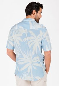 Chemise à manches courtes en tissu bleu clair avec des motifs de feuilles de palmier blanches, un col classique et un ourlet arrondi. Vue arrière.