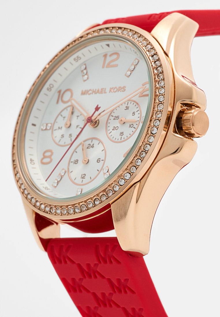 Montre Michael Kors en or rose avec un cadran en cristal, un cadran blanc, trois sous-cadrans et un bracelet en silicone rouge embossé du logo MK.