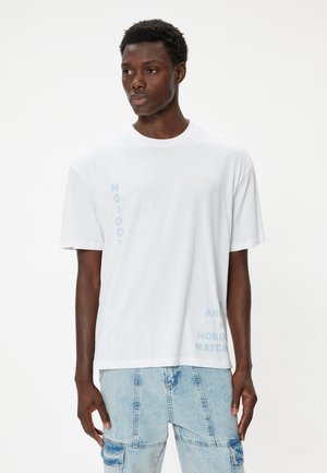 Hvid bomulds t-shirt med vertikale blå tekstgrafik. Løs pasform med korte ærmer og rund hals. Glat tekstur.