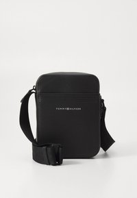 Black rectangular crossbody bag made of textured synthetic material. Features front logo, adjustable strap, and zippered compartments.
