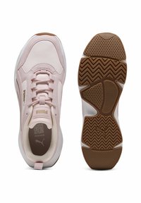 Buty sportowe Puma w miękkim różowym syntetycznym materiale z białymi akcentami, okrągły przód, sznurowana konstrukcja, teksturowana gumowa podeszwa i logo.