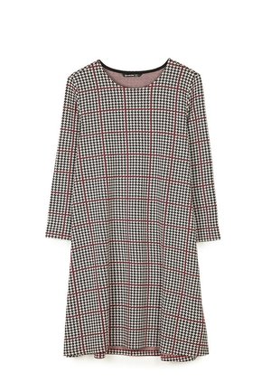 Jurk met lange mouwen met zwart-wit hondentandpatroon, bedekt met fijne rode rasterlijnen, en een ronde halslijn.