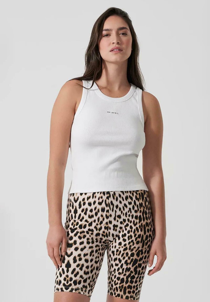 Top in cotone bianco a costine con scollo rotondo, abbinato a pantaloni bike aderenti con motivo leopardato in beige e nero.