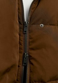 Giacca a vento marrone con una cerniera spessa, tasche laterali e una texture liscia e lucida. Il tessuto ha una leggera brillantezza.