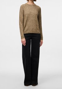 Pull en mélange de laine marron avec un col rond, des manches longues et une coupe décontractée. Associé à un jean noir taille haute à jambes larges.