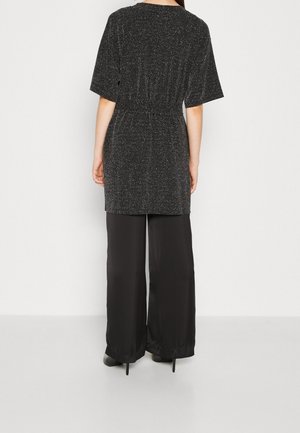 Zwarte, glanzende top met korte mouwen en elastische taille, gecombineerd met elegante, wijde zwarte broek. Glad textuur overal.