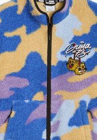 Giacca in pile con motivo camouflage blu, beige e viola. Presenta una cerniera nera e un logo ricamato con teste di tigre in stile cartone animato.