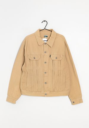 Veste beige boutonnée avec col, deux poches à rabat sur la poitrine et poches fendues latérales, suspendue sur un cintre noir sur fond blanc.
