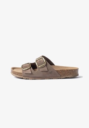 Sandale en daim marron avec deux boucles en laiton réglables et semelle en liège, vue de côté sur fond blanc.