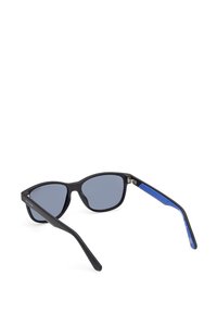 Occhiali da sole neri con lenti grigie, caratterizzati da una forma a occhio di gatto elegante. Le aste hanno un accento testurizzato blu e una finitura opaca.