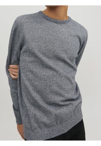 Pull en maille bleu-gris avec un col rond et des manches longues, présentant un motif texturé et une coupe légèrement décontractée.