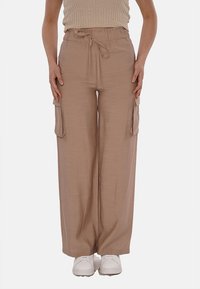 Pantaloni cargo beige a gamba larga con fascia in vita elastica e coulisse regolabile. Presenta due tasche laterali. Realizzati in un tessuto leggero.