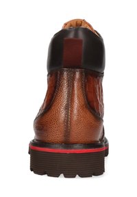 Botín marrón hasta el tobillo con un patrón de cocodrilo texturizado y acentos de cuero suave. Cuenta con una suela de goma con rayas rojas y un panel elástico.