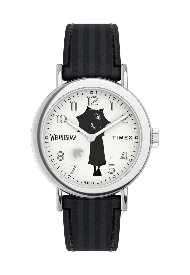 Timex kell, millel on hõbedane roostevabast terasest korpus, valge kellalace, must siluett, musta triibuline nahkrihm ja "Indiglo" funktsioon.