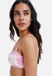 Róża i biała bluzka bandeau w tie-dye, wykonana z teksturowanej tkaniny, z cienkimi ramiączkami, o dopasowanym kroju i marszczonym wzorze.