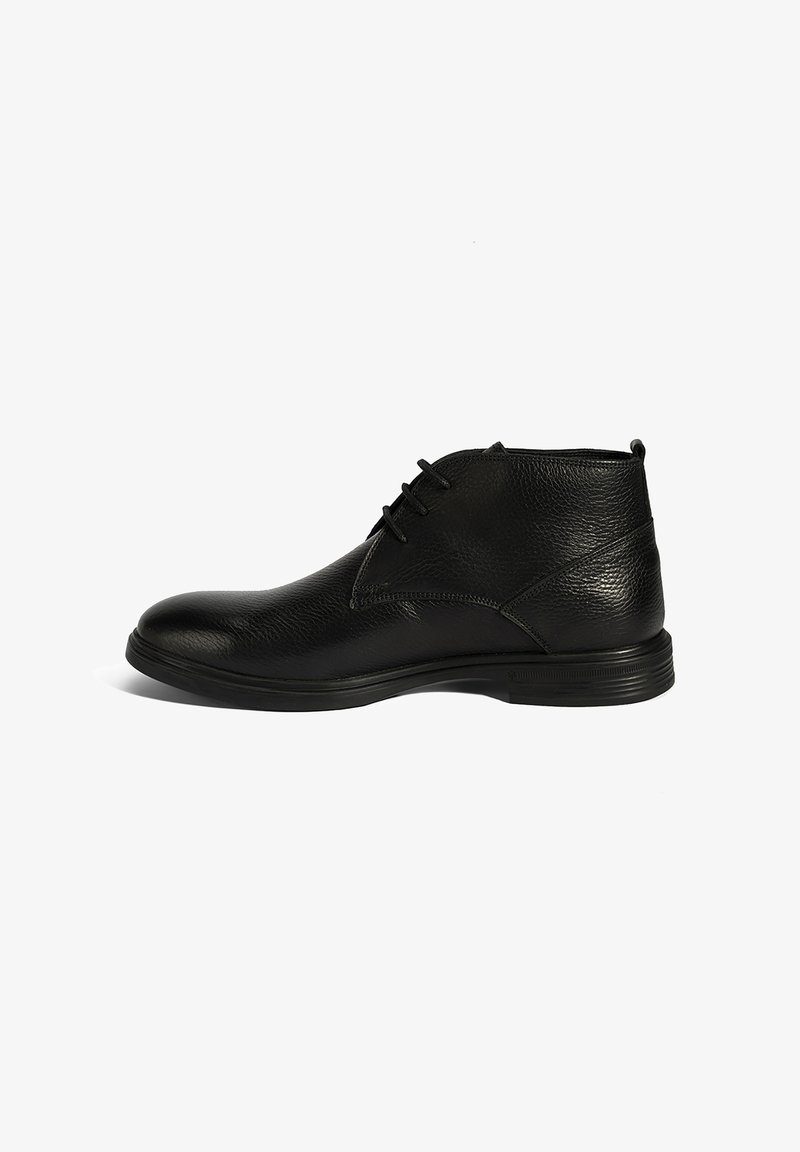 Bottines noires en cuir avec une finition texturée, bout arrondi et lacets. Semelle en caoutchouc avec un motif de tread subtil pour une bonne adhérence.