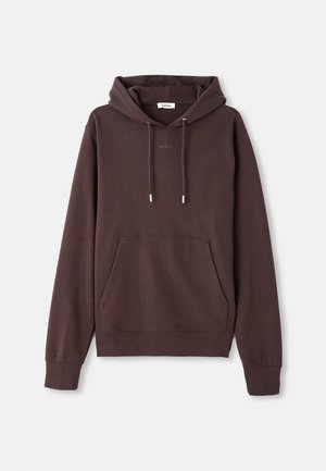 Brun hette laget av myk bomullsblanding, med en frontlomme, justerbar snor og brodert logo detalj nær kragen.