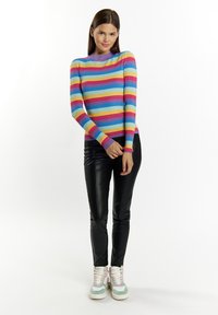 Ribotu, ilgomis rankovėmis megztinis su horizontaliomis juostelėmis rožinės, mėlynos, geltonos ir purpurinės spalvų. Suderintas su juodomis dirbtinėmis odinėmis kelnėmis ir daugiakampėmis sportbačiais.