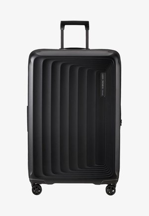 Black hardshell suitcase with grooved design, telescopic handle, and four spinner wheels. Features a zipper closure and logo details.
